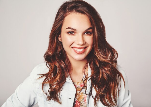 Portrait of young stylish laughing model in colorful casual summer clothes with natural makeup on gray