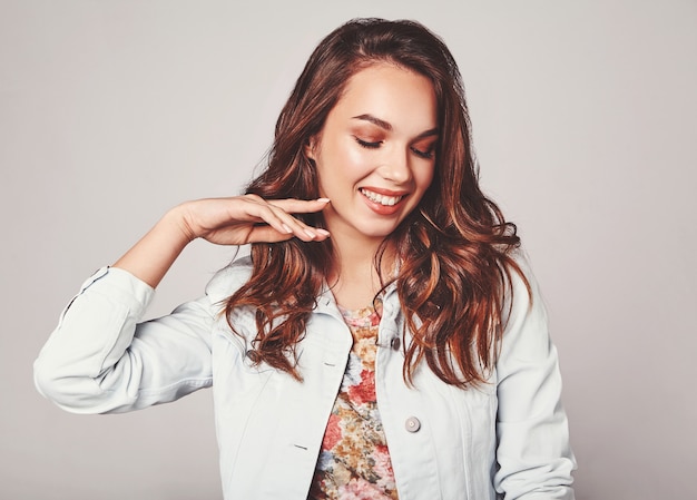 Portrait of young stylish laughing model in colorful casual summer clothes with natural makeup on gray