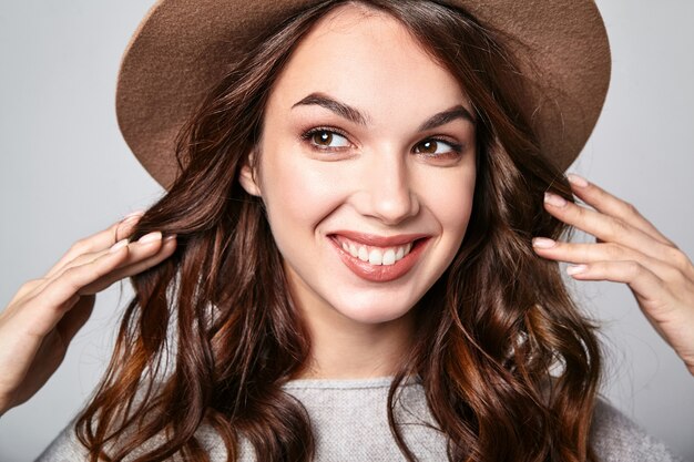 Portrait of young stylish laughing model in gray casual summer clothes in brown hat