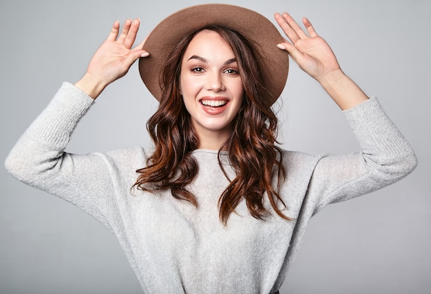 Portrait of young stylish laughing model in gray casual summer clothes in brown hat