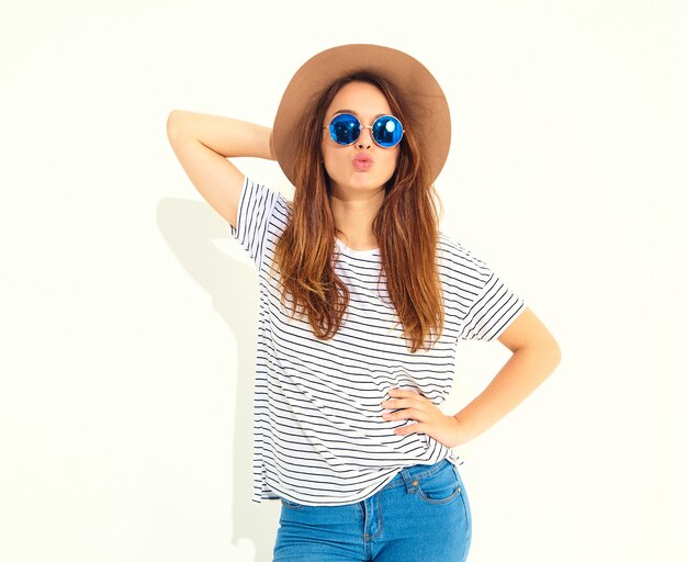 Portrait of young stylish laughing woman model in casual summer clothes in brown hat isolated on white wall