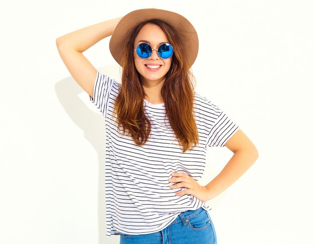 Portrait of young stylish laughing woman model in casual summer clothes in brown hat isolated on white wall