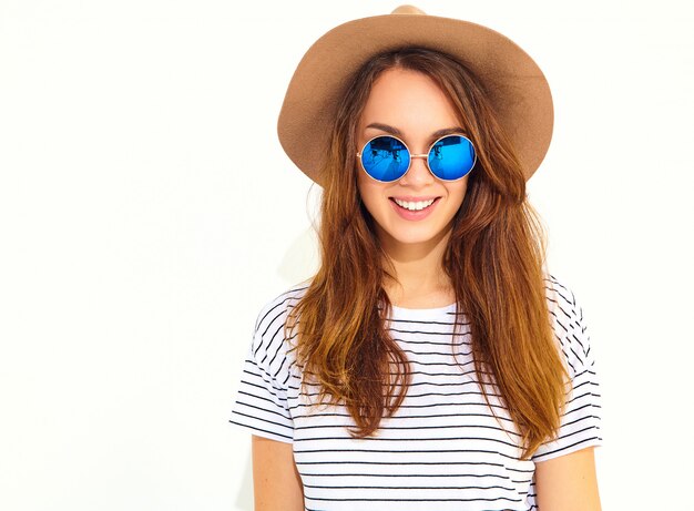 Portrait of young stylish laughing woman model in casual summer clothes in brown hat isolated on white wall