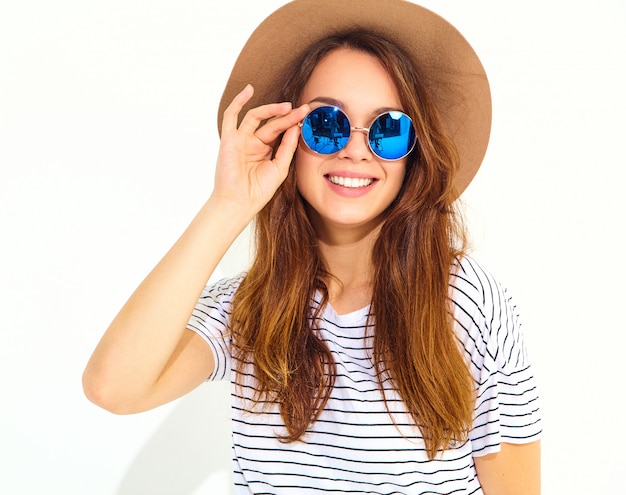 Portrait of young stylish laughing woman model in casual summer clothes in brown hat isolated on white wall