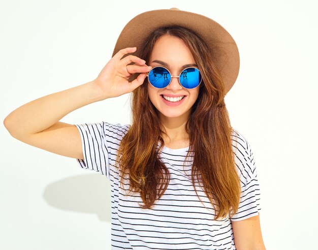 Portrait of young stylish laughing woman model in casual summer clothes in brown hat isolated on white wall