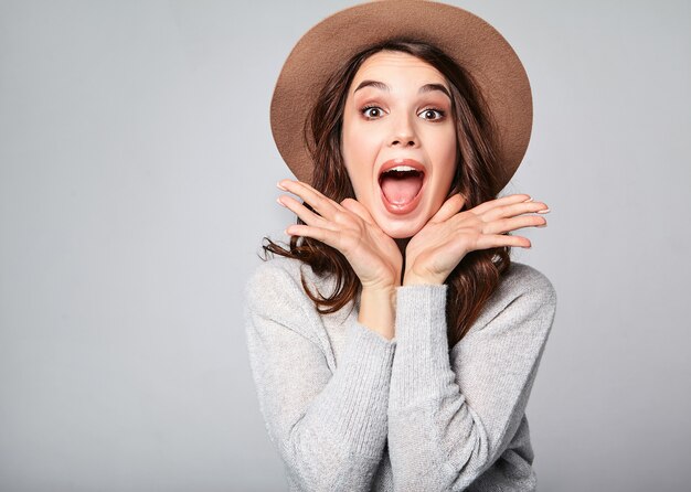 Portrait of young stylish  model excited screaming shocked in gray casual summer clothes in brown hat