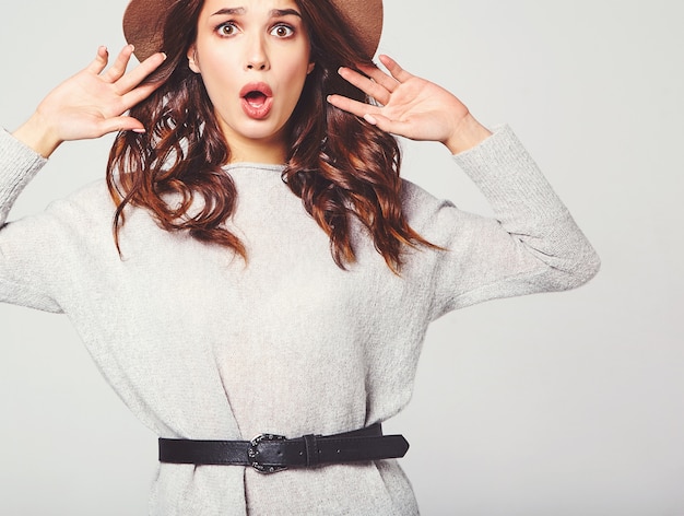 Portrait of young stylish model with facial expression of surprise in gray casual summer clothes in brown