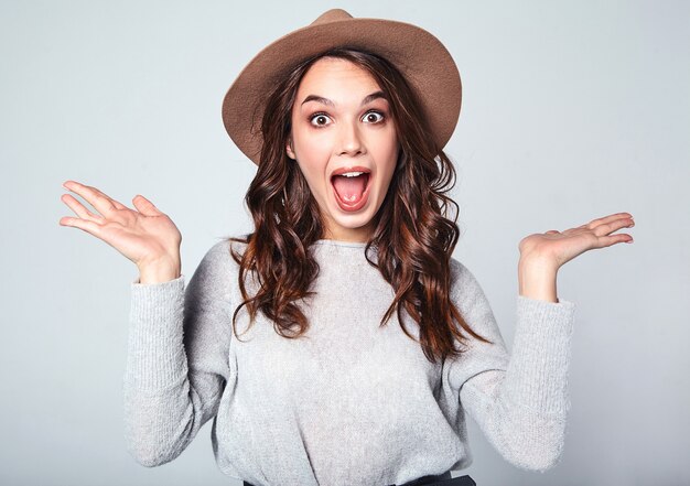 Portrait of young stylish model with facial expression of surprise in gray