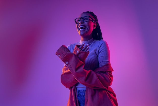 Portrait of young stylish woman smiling laughing posing isolated over gradient pink purple background