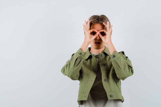 Foto gratuita ritratto di giovane ragazzo adolescente che mostra gesto di occhiali in t-shirt