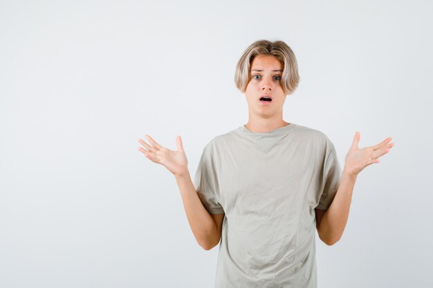 Portrait of young teen boy showing helpless gesture in t-shirt and looking puzzled front view