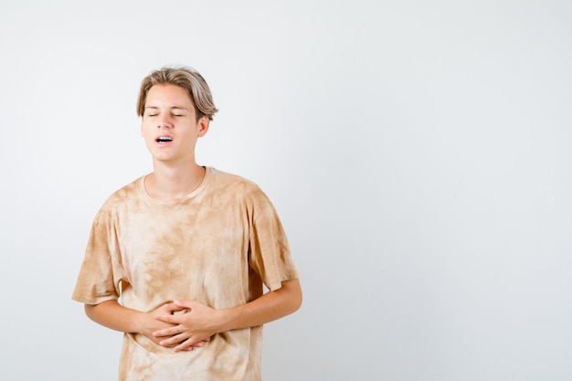 Portrait of young teen boy suffering from stomach pain in t-shirt and looking bothered front view