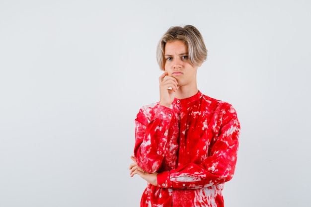 Portrait of young teen boy with hand on chin in shirt and looking disappointed front view