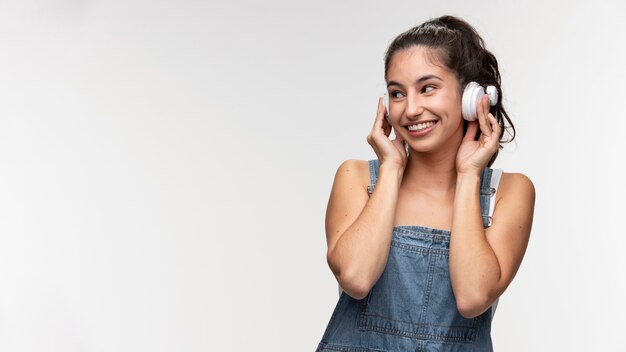 ヘッドフォンで音楽を聴いているオーバーオールの若い10代の少女の肖像画