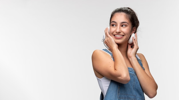 Free photo portrait of young teenage girl in overalls listening to music on headphones