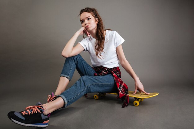 Portrait of a young teenage girl sitting on skateboard