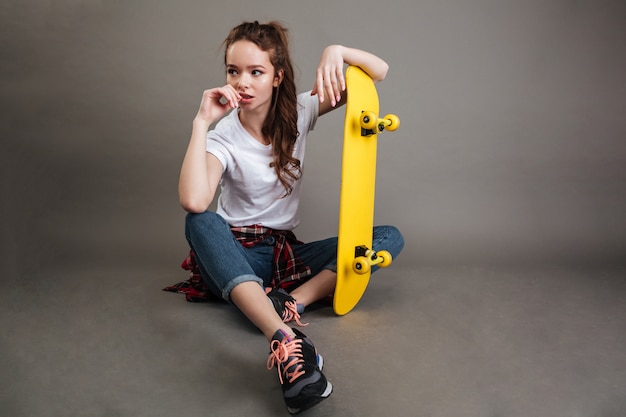 スケートボードで座っている若い10代の少女の肖像画