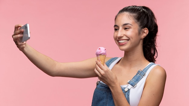 Foto gratuita ritratto di giovane adolescente che prende un selfie mentre tiene il gelato