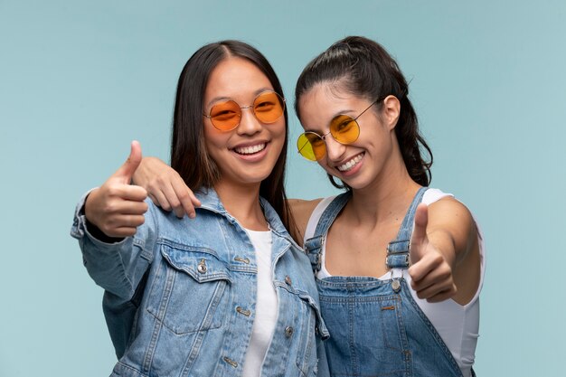 Portrait of young teenage girls with sunglasses showing thumbs up