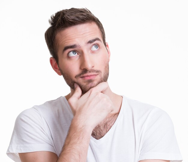 Portrait of the young thinking man looks up in casuals isolated on white background.