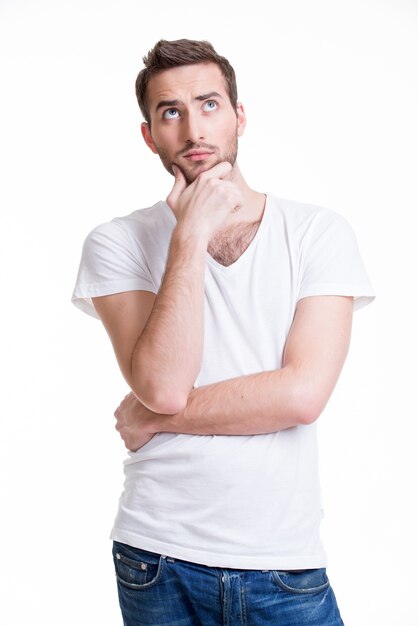 Portrait of the young thinking man looks up in casuals isolated