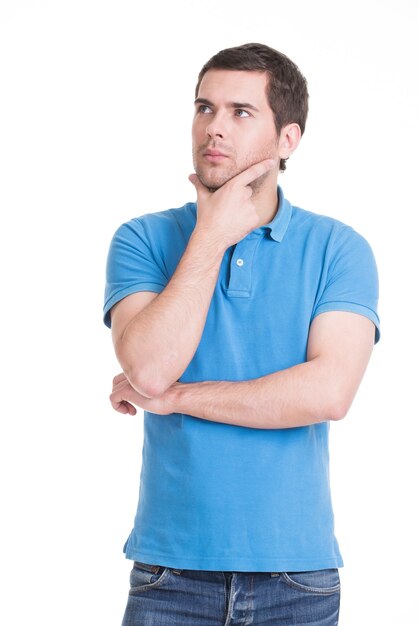 Portrait of the young thinking man looks up with hand near face -  isolated on white.