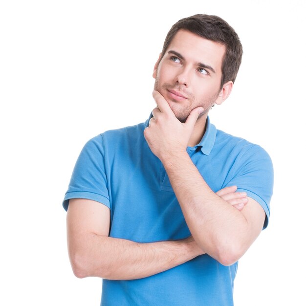 Portrait of the young thinking man looks up with hand near face