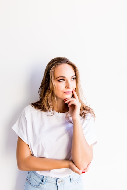 Portrait of the young thinking woman looking up sideways on white background.