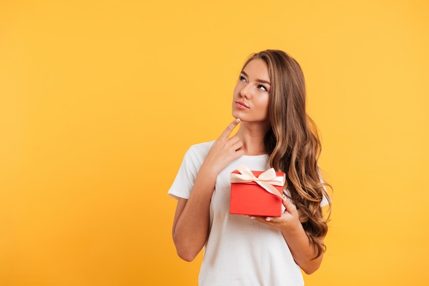 Portrait of a young thoughtful girl holding gift box