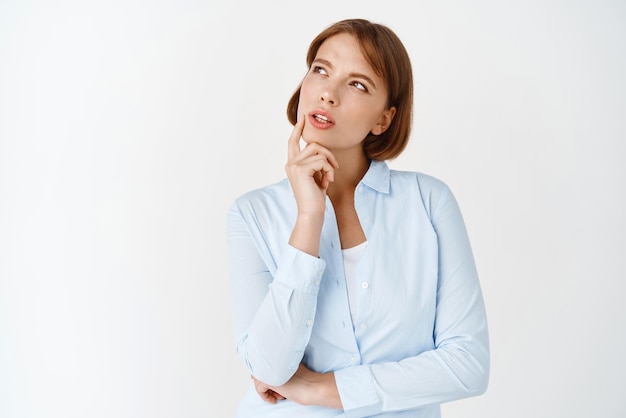Портрет молодой задумчивой женщины, которая смотрит в сторону на логотип, думает и делает выбор, обдумывая решение, стоя в блузке на белом фоне