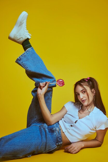 Portrait of young woman in 2000s fashion style posing with lollipop