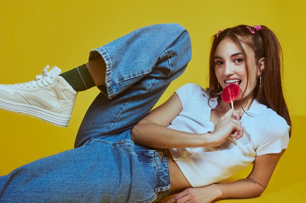Portrait of young woman in 2000s fashion style posing with lollipop