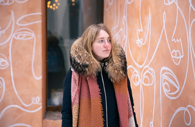 Portrait of a young woman against an orange wall with drawings winter portrait