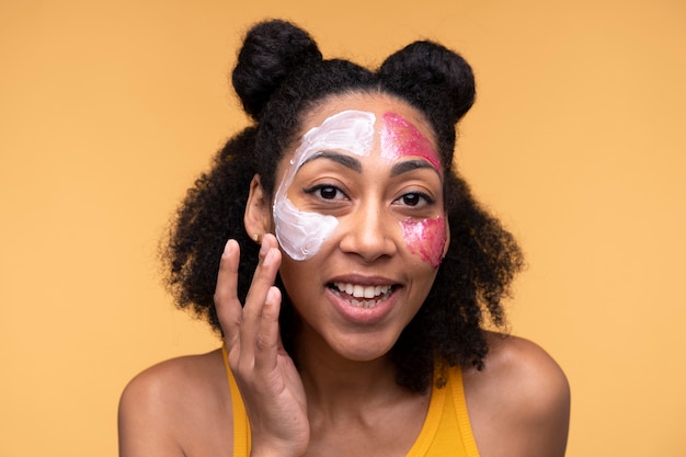 保湿剤とフェイスマスクを適用する若い女性の肖像画