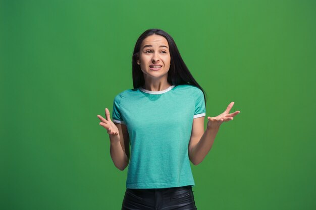 Portrait of young woman arguing on green wall