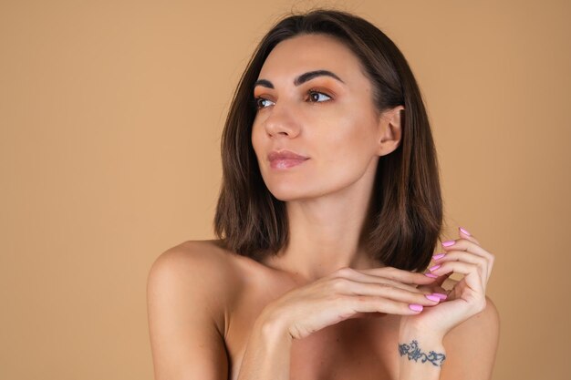 Portrait of a young woman on a beige wall with natural warm make-up, and smooth clean skin