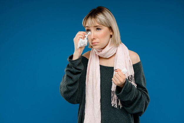 Portrait of young woman being ill over blue wall