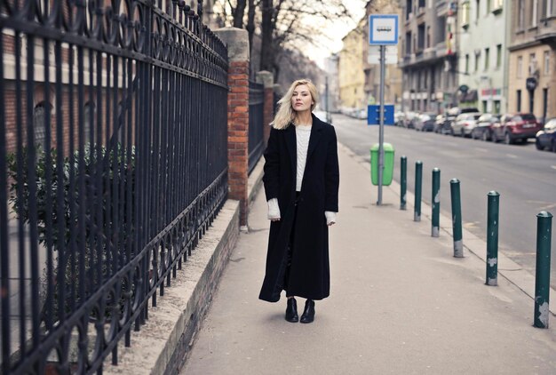 портрет молодой женщины в черном пальто на улице