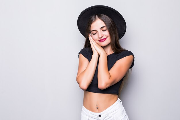Portrait of young woman in black floppy hat on gray background