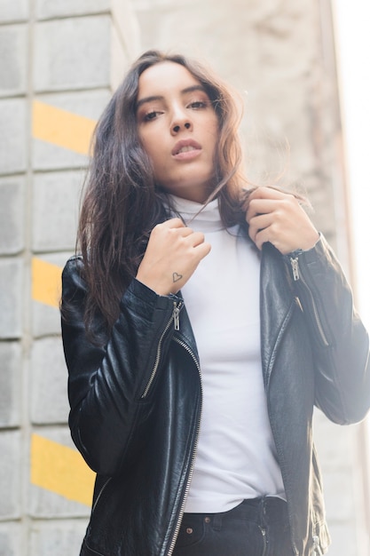 Portrait of a young woman in black leather jacket looking at camera