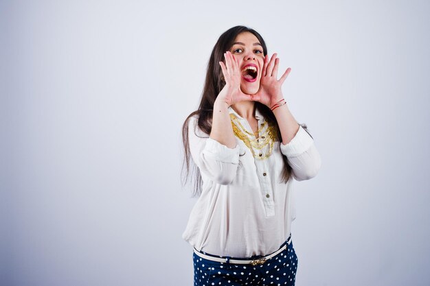 Portrait of a young woman in blouse and blue trousers screaming