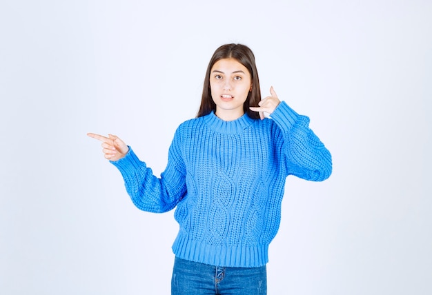 Портрет молодой женщины в голубом свитере, стоя на белом.