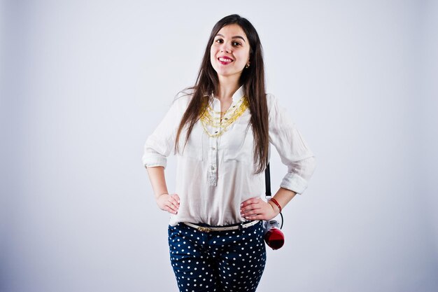 Free photo portrait of a young woman in blue trousers and white blouse posing with megaphone in the studio