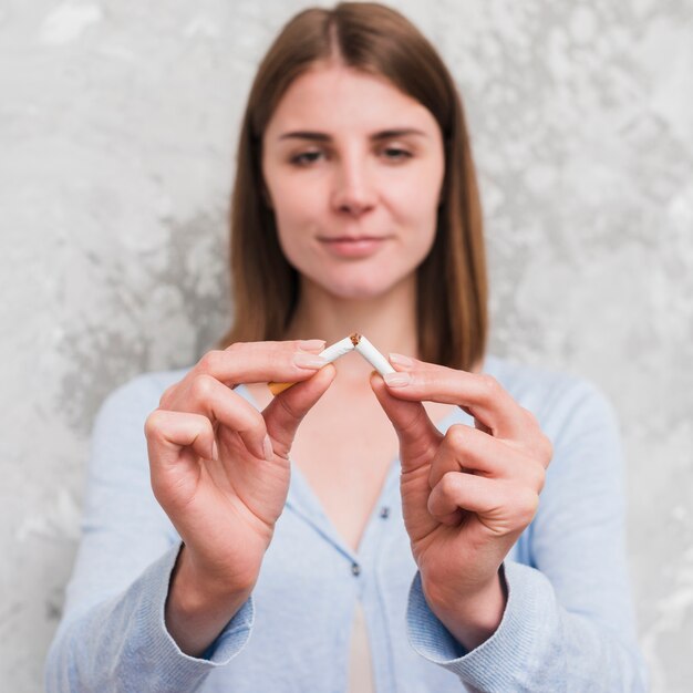 Portrait of young woman breaking cigarette