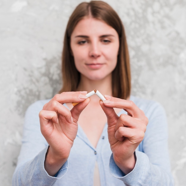 portrait of young woman breaking cigarette