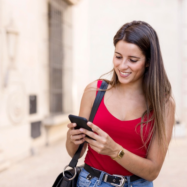 Foto gratuita ritratto di giovane donna che passa in rassegna il telefono cellulare