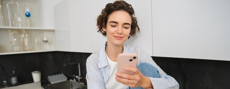 Free Photo portrait of young woman checking her mobile phone reading message on smartphone and smiling