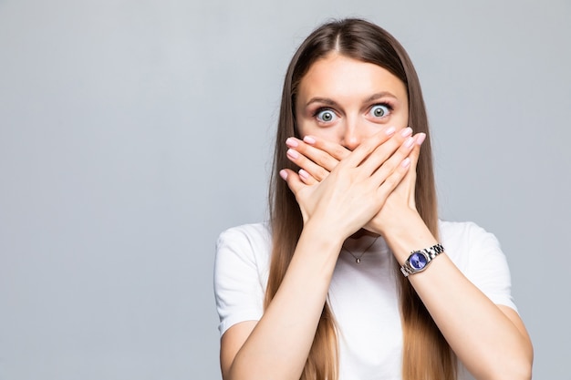 Portrait of young woman covering mouth with hand isolated