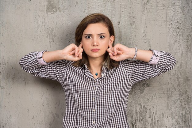 Portrait of young woman covering with hands her ears