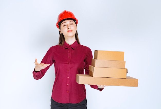 Portrait of a young woman in crash helmet holding paper boxes . 